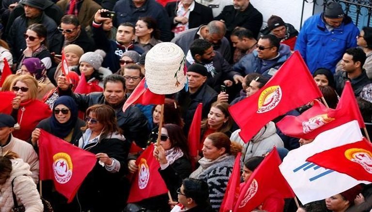 متظاهرون يحملون علم اتحاد الشغل التونسي - رويترز