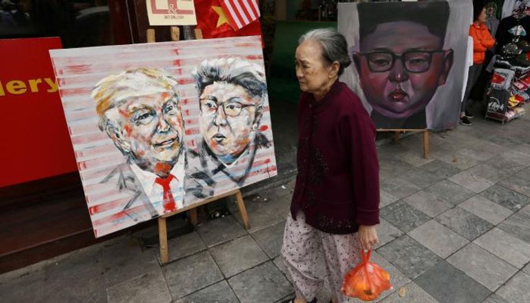امرأة تسير أمام لوحات كيم وترامب في هانوي
