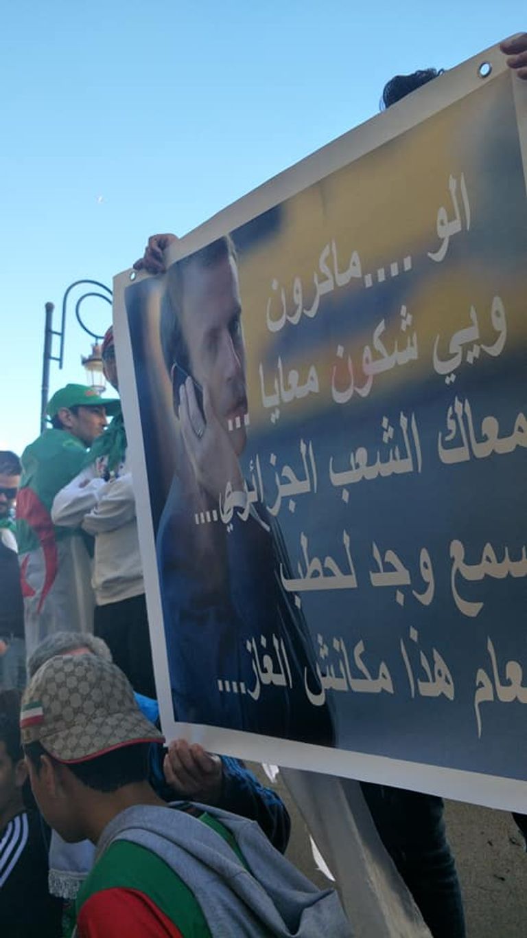 لافتة موجهة للرئيس الفرنسي طفل يحمل راية الجزائر على ظهر جده في مظاهرات الجمعة