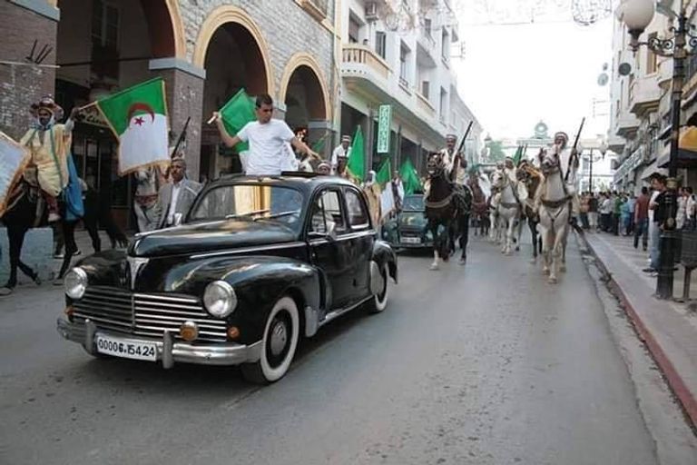 جزائريون يعيديون تجسيد وقائع استقلال الجزائر طفل يحمل راية الجزائر على ظهر جده في مظاهرات الجمعة
