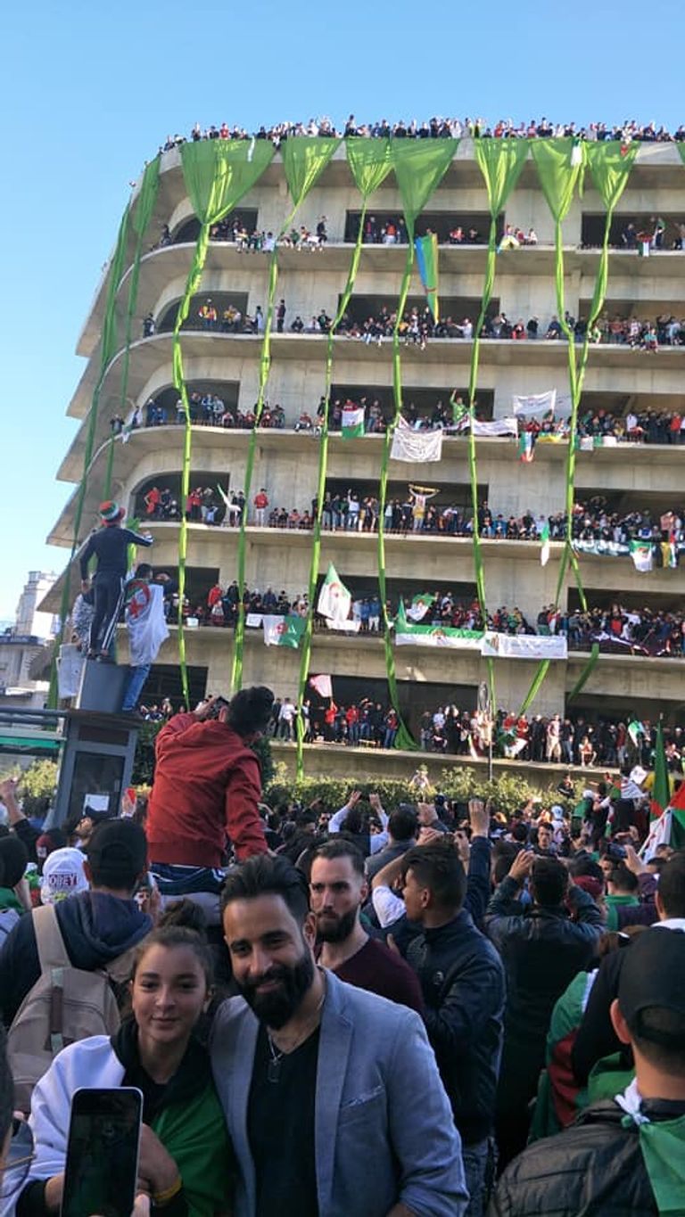 جزائريون في مبنى غير مكتمل طفل يحمل راية الجزائر على ظهر جده في مظاهرات الجمعة