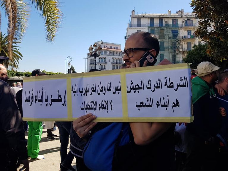 لافتات الجزائريين في مظاهراتهم طفل يحمل راية الجزائر على ظهر جده في مظاهرات الجمعة