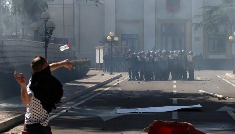 متظاهر يلقي قوات الشرطة بالحجارة أمام مقر البرلمان بألبانيا - أرشيفية