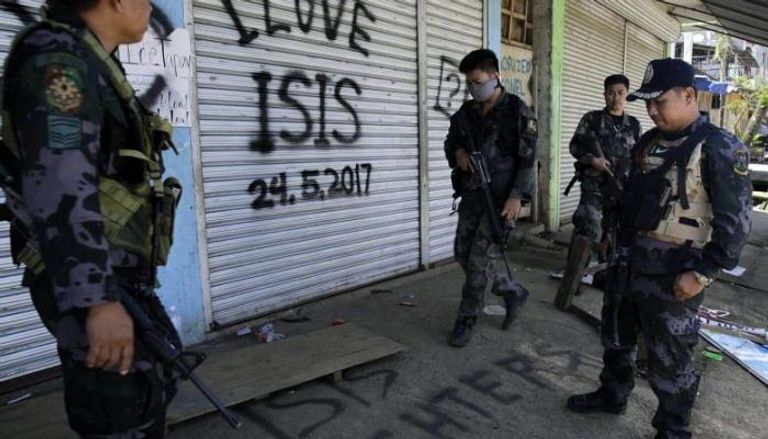 عناصر من الجيش الفلبيني أمام شعارات كتبها إرهابيو تنظيم داعش