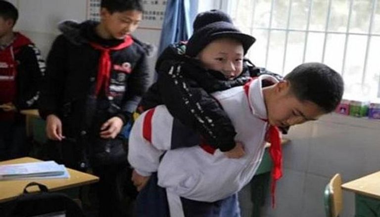الطالب الصيني "زو بينجيانج" يحمل زميله على ظهره كل يوم إلى المدرسة