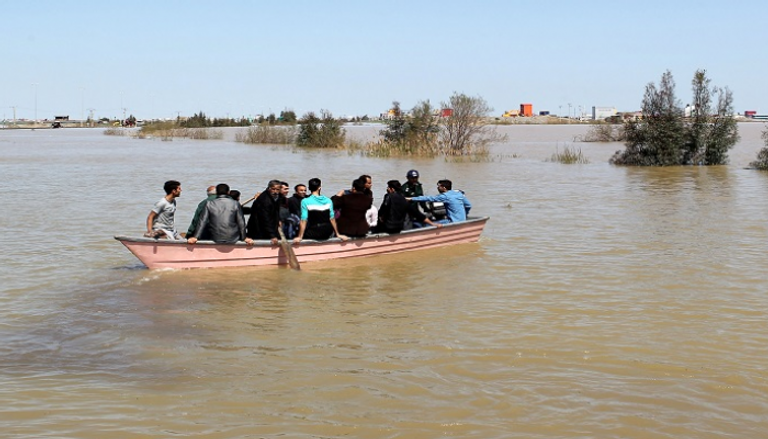 عائلة على متن قارب بعد حدوث فيضان بمقاطعة جولستان الإيرانية - رويترز