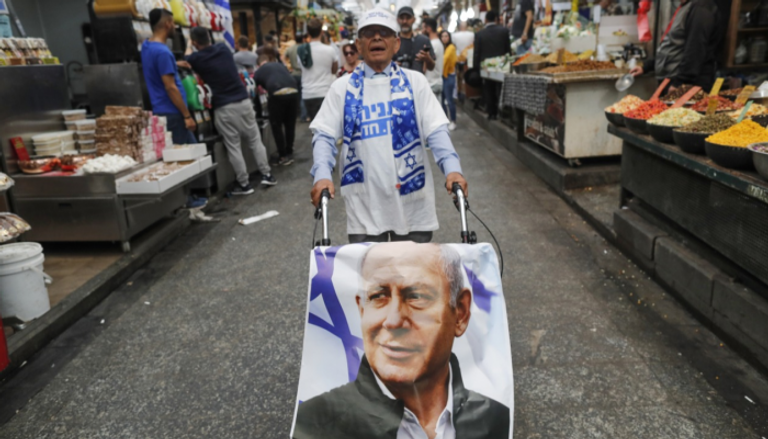إسرائيلي يسير بملصق لنتنياهو  في أحد أسواق تل أبيب