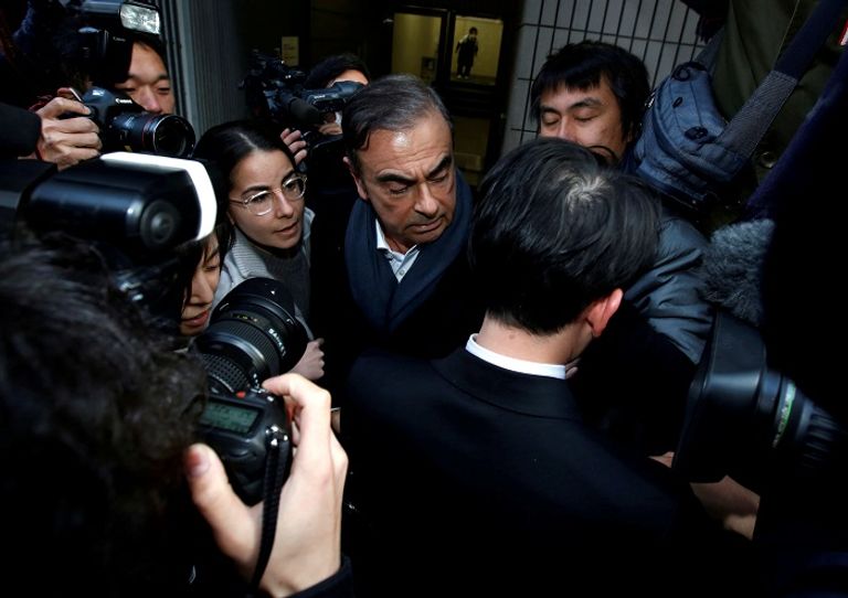 محامي غصن يسير أمام شاشة تظهر فيديو لرئيس نيسان السابق