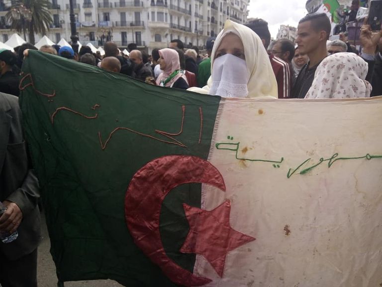 جزائرية تحمل علم والدها الشهيد في الثورة التحريرية مطلخاً بدمه مظاهرات في الجزائر مطالبة بتغيير كل نظام بوتفليقة