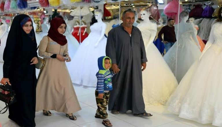 عراقيون يمرون أمام متجر لبيع فساتين أعراس 