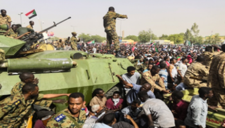 سودانية تقدم قارورة ماء لعسكري أثناء تجمع أمام مقر قيادة الجيش بالخرطوم