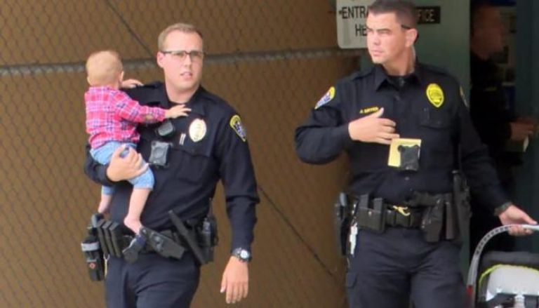ضباط الشرطة يحملون الطفل بعد الحادث