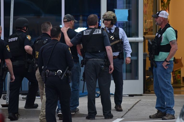 الشرطة الأمريكية في منطقة حادث مدرسة كولورادو شرطي يتحدث مع أولياء الأمور عقب حادث مدرسة كولورادو (أ.ف.ب)