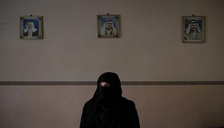 خديجة تجلس أمام صور زوجها وشقيقه اللذين قتلا على يد فلول داعش
