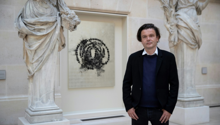 الفنان جان ميشال أوتونييل أمام إحدى اللوحات المعروضة في متحف اللوفر
