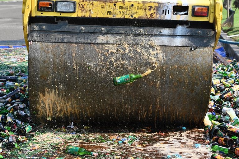 عربة ذات عجلات سميكة تسحق الآلاف من زجاجات الكحول