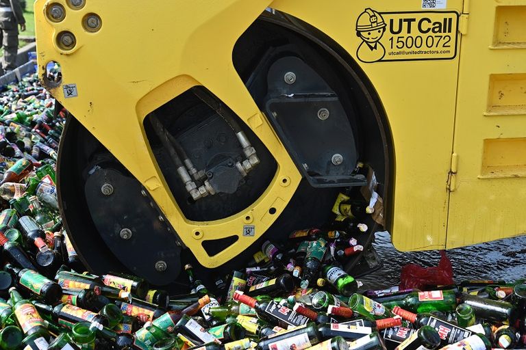 عربة ذات عجلات سميكة تسحق الآلاف من زجاجات الكحول