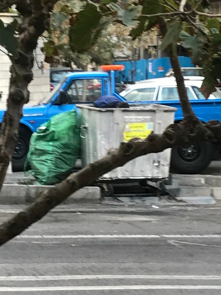 مراهق إيراني يفتش في صندوق قمامة إيرانية تفتش في أحد صناديق القمامة بحثا عن طعام - أرشيفية