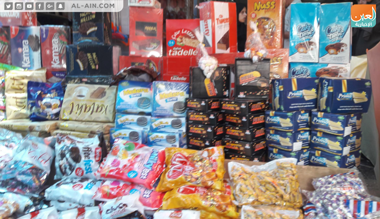 فلسطينية برفقة ابنتها تشتري الحلوى في أحد محال غزة