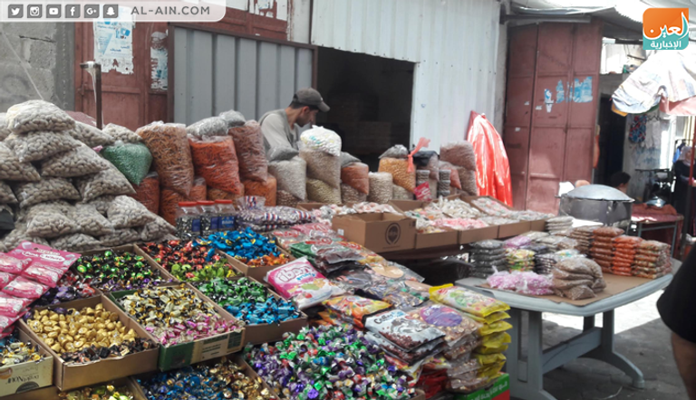 فلسطينية برفقة ابنتها تشتري الحلوى في أحد محال غزة