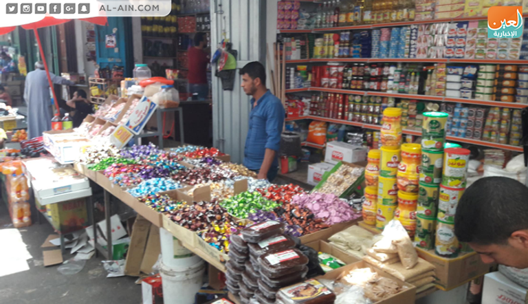 فلسطينية برفقة ابنتها تشتري الحلوى في أحد محال غزة