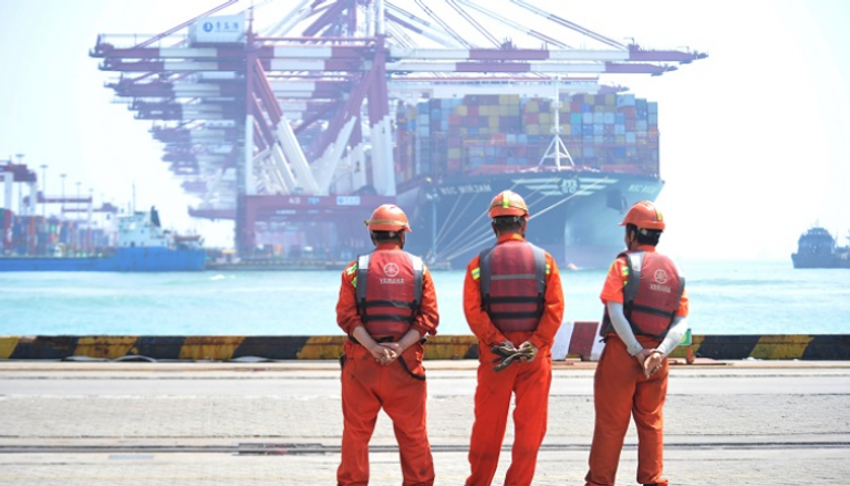 عمال يقفون في ميناء تشينغداو الصيني- رويترز