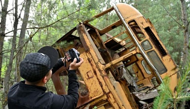 زائر يلتقط صورة مع إحدى المركبات بموقع الكارثة 