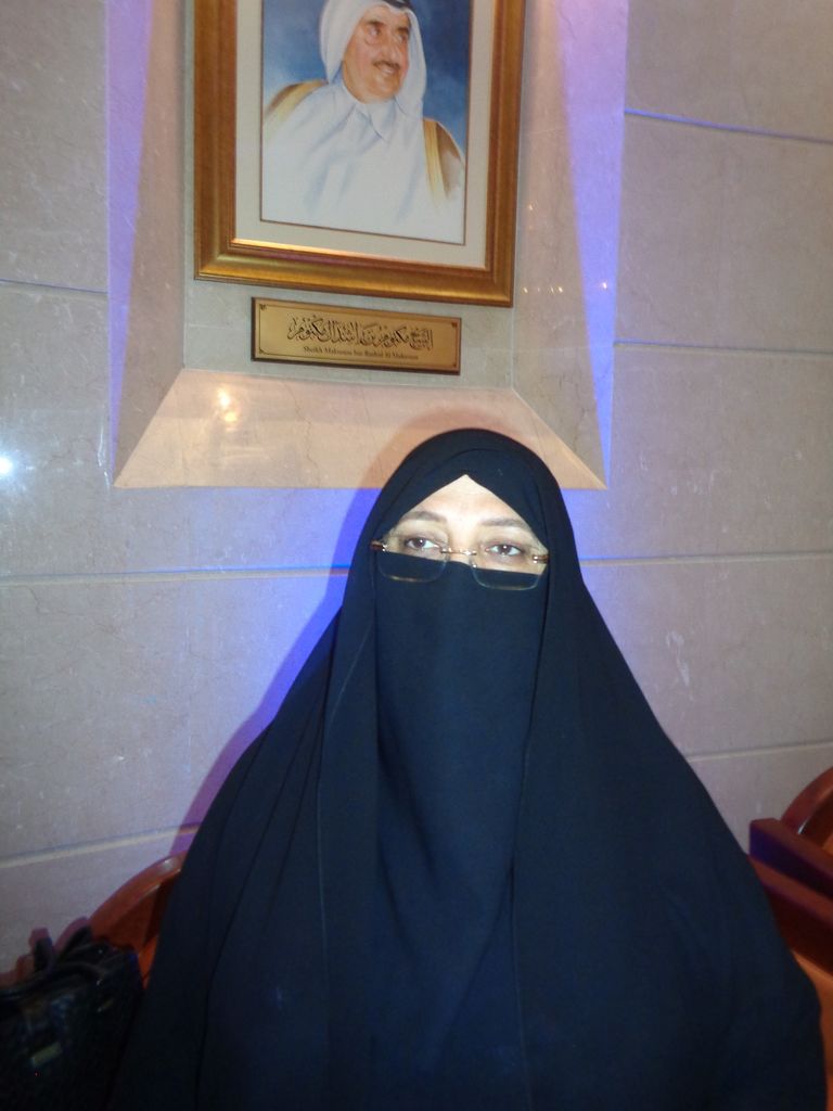 الرسامة الإماراتية منى الخاجة بجانب لوحتها "مسجد البدية"