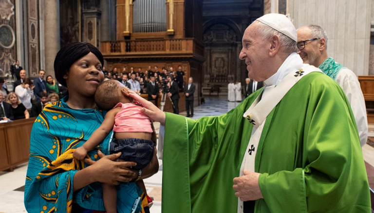 البابا فرنسيس يتحدث إلى إحدى المهاجرات خلال القداس