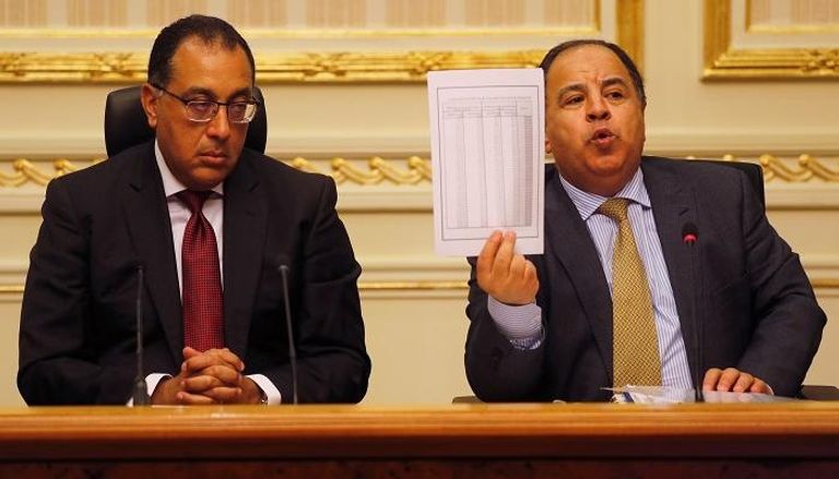 وزير المالية المصري يلوح بورقة بجوار رئيس الوزراء - رويترز 