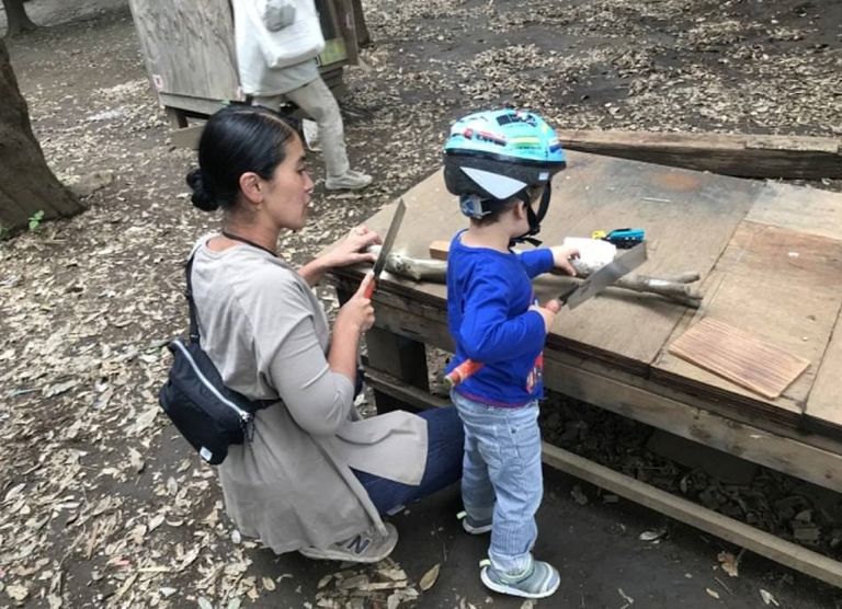 طفل بالحديقة يستخدم مطرقة على لوح خشب