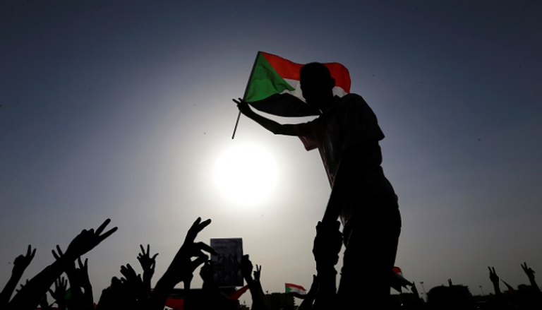 سودانيون يرفعون علم بلادهم - رويترز