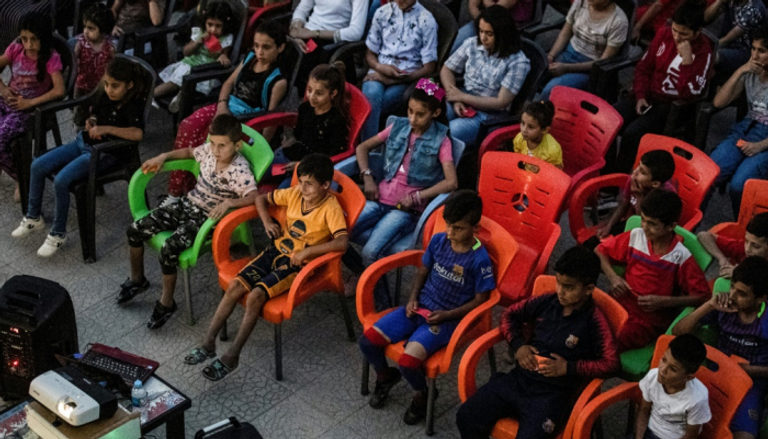أطفال يحضرون عرض فيلم لتشارلي تشابلن في مدرسة سورية