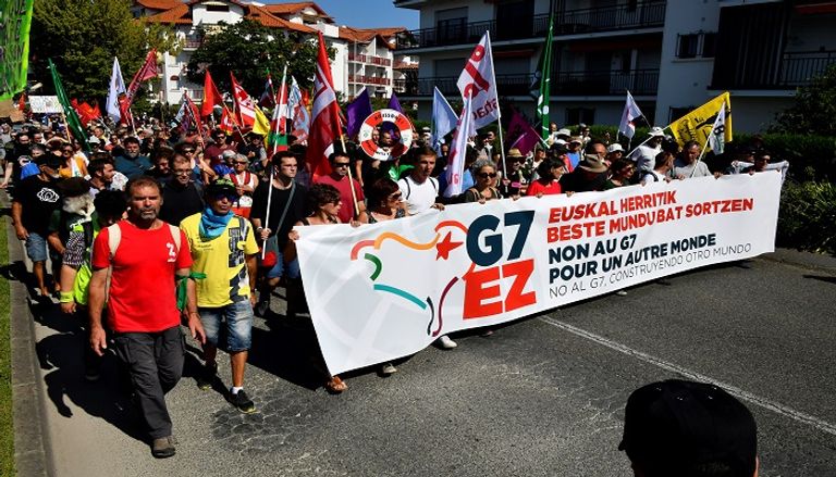 متظاهر يبعد قنبلة غاز عن محيط المظاهرات - الفرنسية