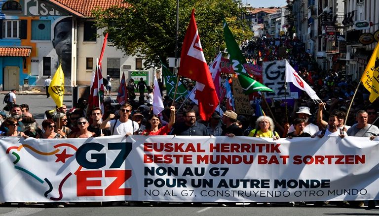 متظاهر يبعد قنبلة غاز عن محيط المظاهرات - الفرنسية