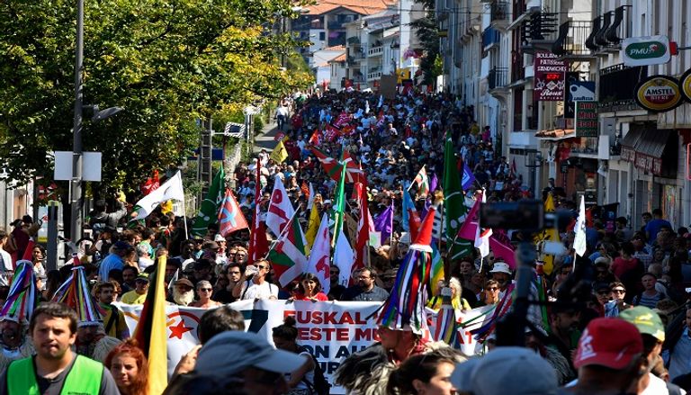 متظاهر يبعد قنبلة غاز عن محيط المظاهرات - الفرنسية