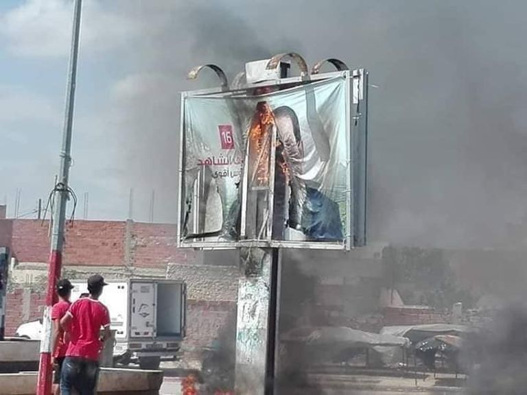 تونسيون يحرقون لافتة للشاهد في أحد شوارع البلاد