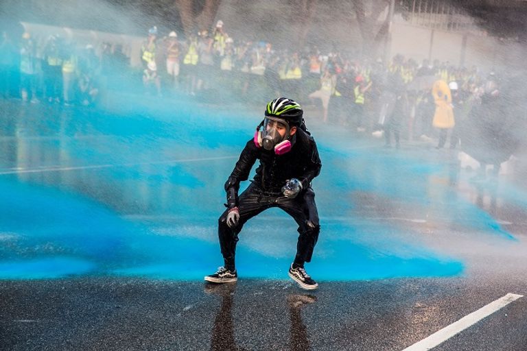 جانب من المواجهات بين الشرطة والمحتجين في هونج كونج متظاهر يرمي مولوتوف فوق حاجز خارج مقر الحكومة