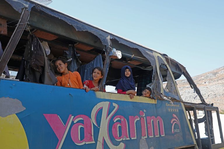 أم جمعة وأولادها أمام الحافلة التي اتخذوها منزلا لهم