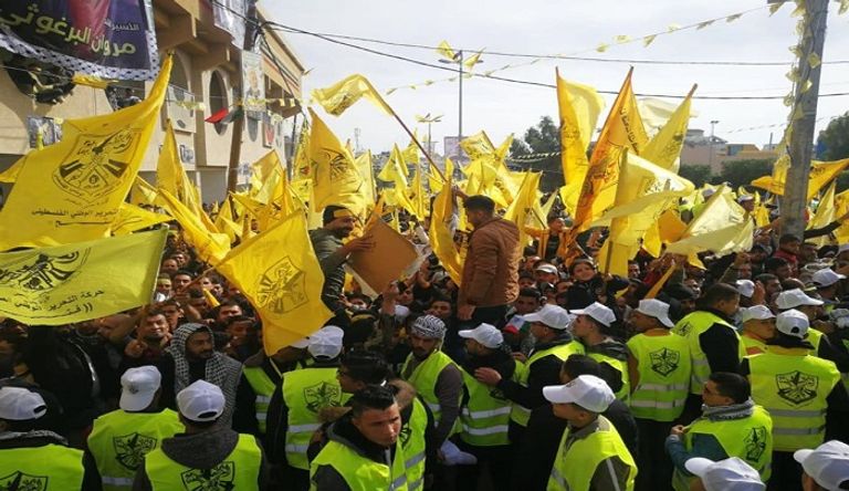 فلسطينية تتوشح بعلم حركة فتح وتحمل صورة الرئيس عباس