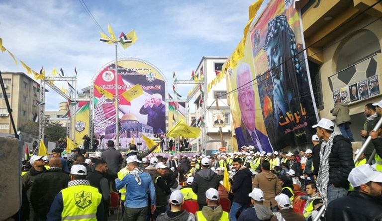 فلسطينية تتوشح بعلم حركة فتح وتحمل صورة الرئيس عباس