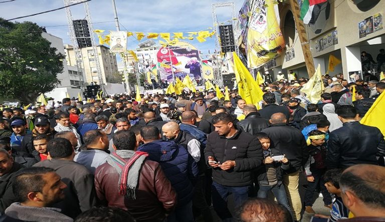 فلسطينية تتوشح بعلم حركة فتح وتحمل صورة الرئيس عباس