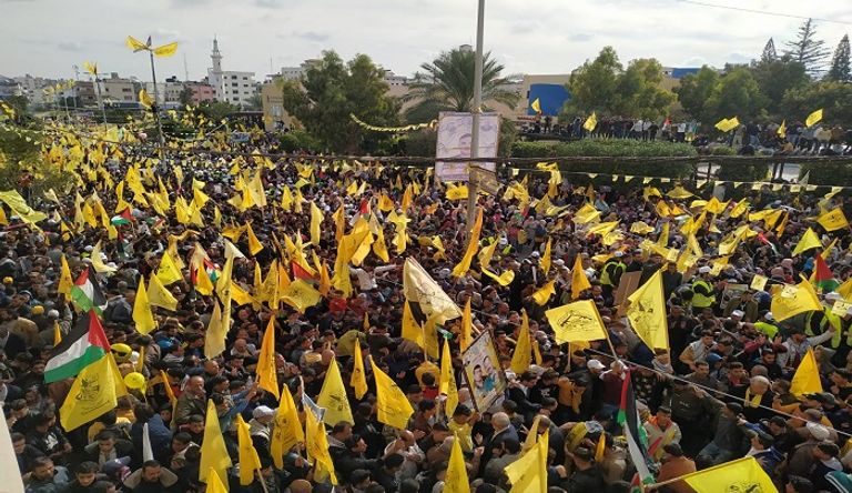 فلسطينية تتوشح بعلم حركة فتح وتحمل صورة الرئيس عباس