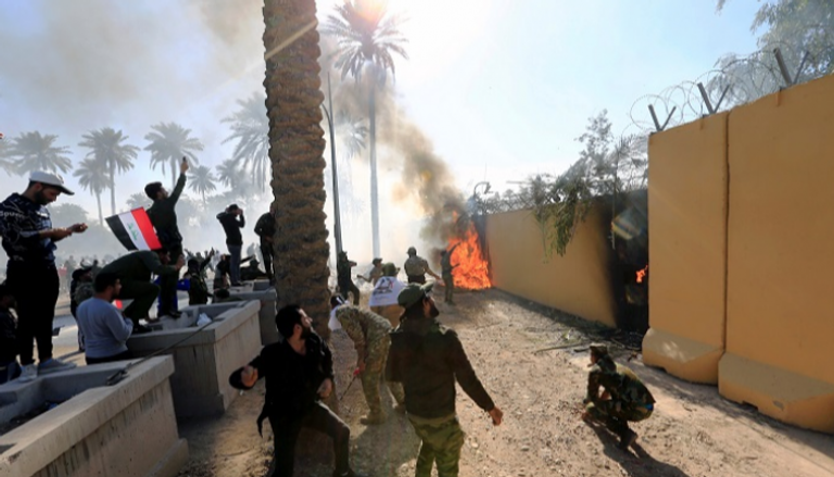 عناصر مليشيا حزب الله العراقية يضرمون النيران بسور السفارة