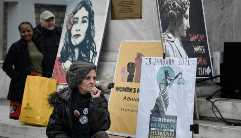 امرأة تجلس بالقرب من شعارات رفعت في تظاهرة لمناهضة العنف ضد النساء 