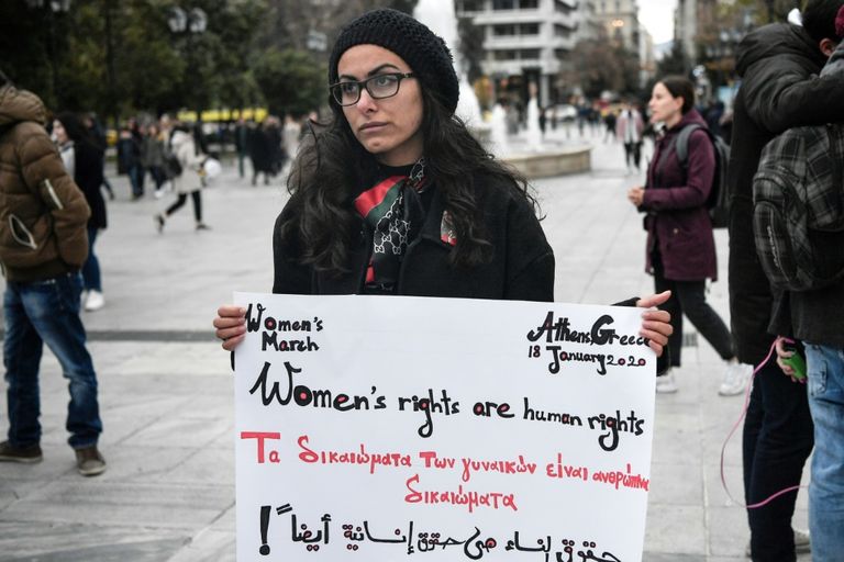 امرأة تجلس بالقرب من شعارات رفعت في تظاهرة لمناهضة العنف ضد النساء