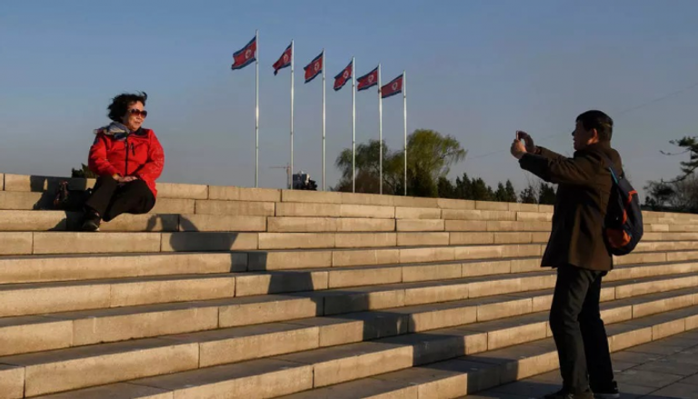 سائح صيني يلتقط صورة لزوجته قرب علم كوريا الشمالية.. أرشيف