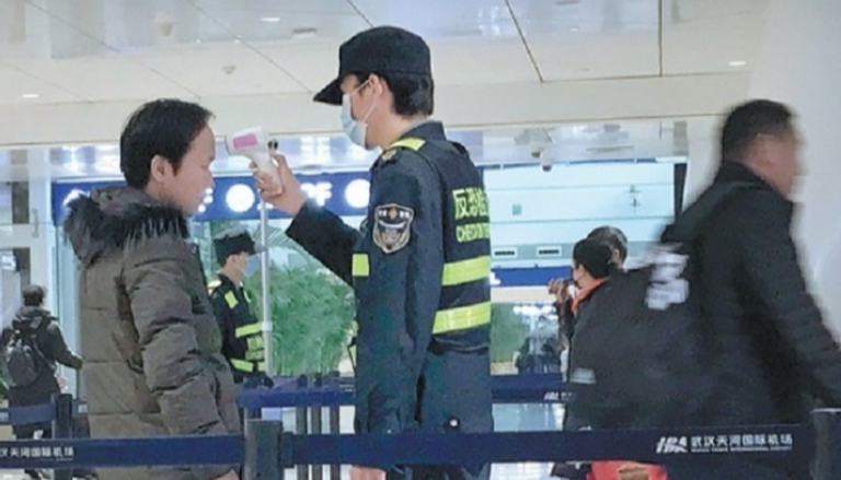 مسؤول يفحص أحد الركاب في مطار ووهان