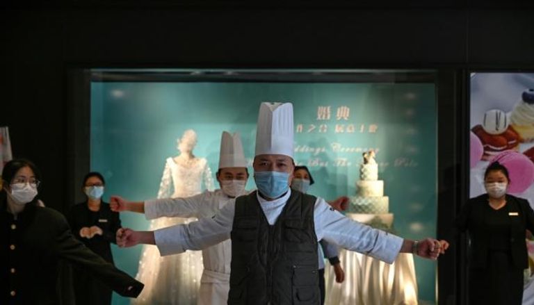 موظفون صينيون يضعون أقنعة واقية خلال اجتماع بشأن كورونا 