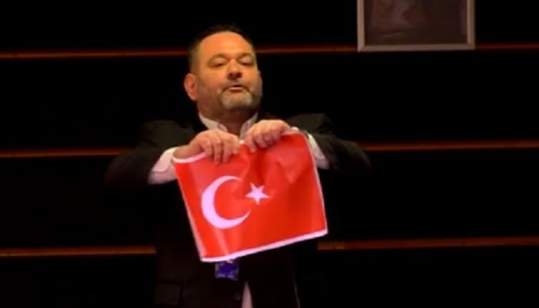 النائب اليوناني خلال تمزيق العلم التركي